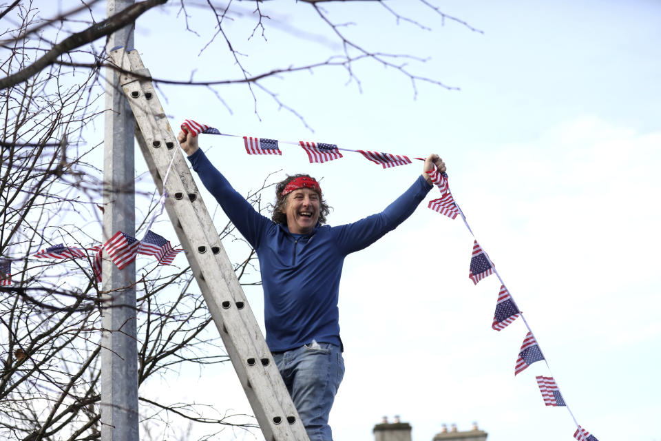 A man puts bunting up in the town of Ballina, the ancestral home of Joe Biden, in North West of Ireland, Saturday, Nov. 7, 2020. Biden was elected Saturday as the 46th president of the United States, defeating President Donald Trump in an election that played out against the backdrop of a pandemic, its economic fallout and a national reckoning on racism. (AP Photo/Peter Morrison)