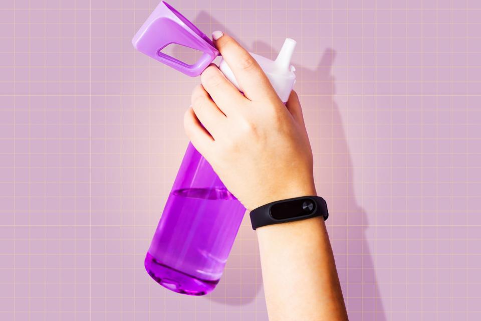 Hand holding a water bottle on a designed background