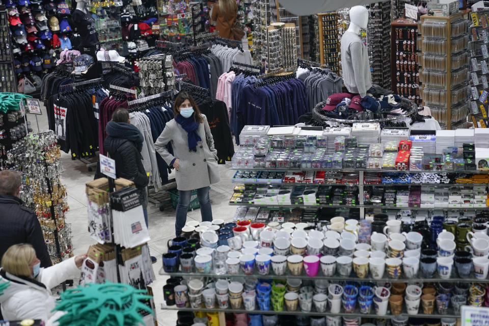 People shop at Grand Slam, a souvenir and sports apparel store, in Times Square, Monday, Nov. 15, 2021, in New York. Even as visitors again crowd below the jumbo screens in New York’s Times Square, the souvenir shops, restaurants, hotels and entrepreneurs within the iconic U.S. landmark are still reeling from a staggering pandemic. (AP Photo/Seth Wenig)