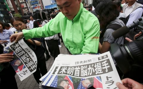 A staff of a Japanese news paper Yomiuri distributes an extra edition of the newspaper reporting the summit - Credit: Koji Sasahara/AP