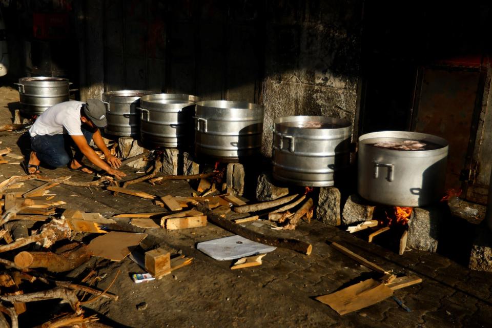 2023年10月15日，加薩南部甘尤尼斯居民用柴火煮大鍋菜，要供應給其他難民吃。路透社