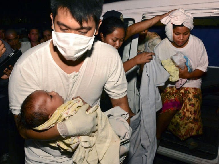 A medic carries rescued three-month-old Trisia Mae Kumaro along with her mother (back) after they were rescued from a sea collision in Cebu, central Philippines on August 16, 2013. Philippine rescuers battled stormy weather Saturday in the search for 171 people missing after a crowded ferry collided with a cargo ship and sank almost instantly, with 31 confirmed dead