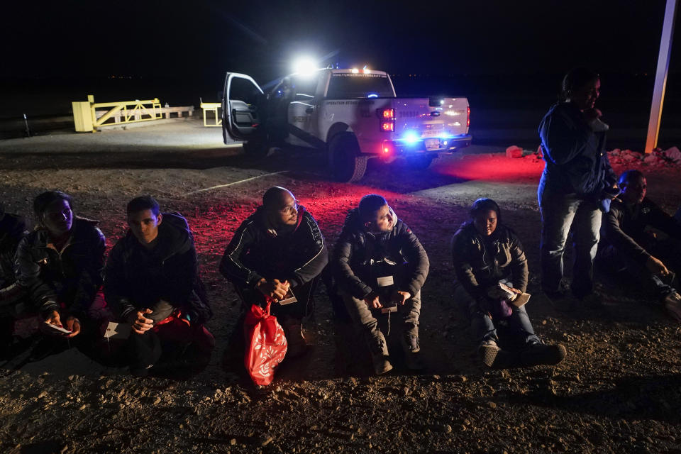 Migrants wait to be processed after crossing the border Friday, Jan. 6, 2023, near Yuma, Arizona. The Biden administration on Thursday launched an online appointment system for migrants to be exempt from limits on seeking asylum, its latest major step in eight days to overhaul border enforcement. (AP Photo/Gregory Bull)