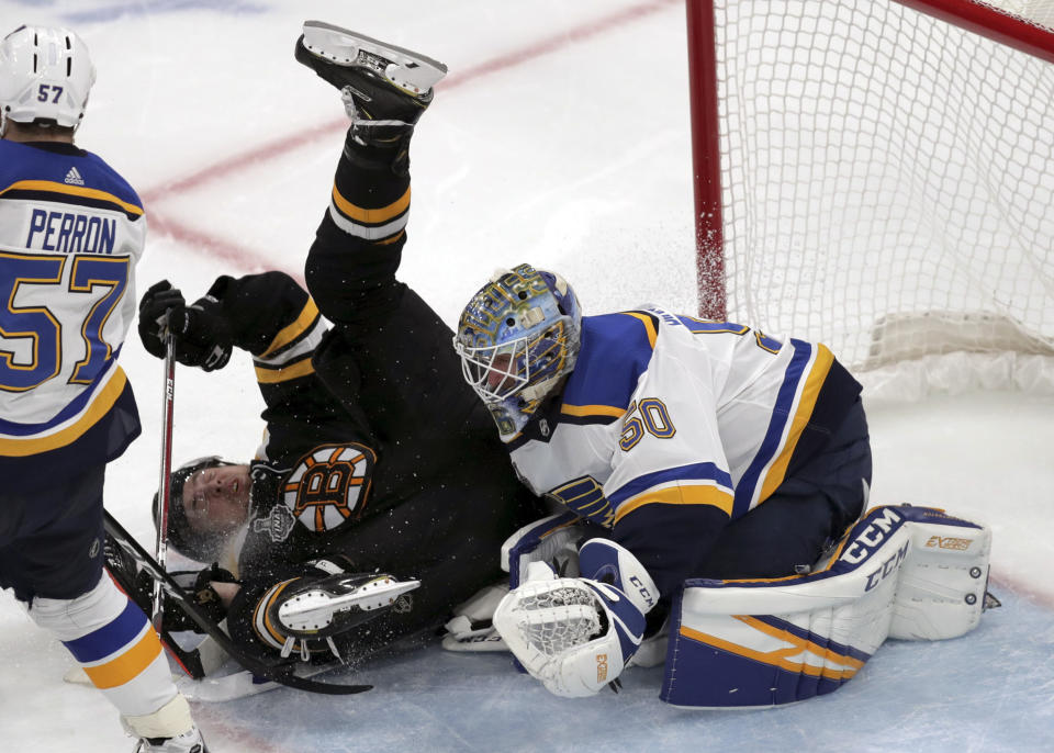 Boston Bruins' Charlie McAvoy, left, crashes to the ice in front of St. Louis Blues goaltender Jordan Binnington during the third period in Game 7 of the NHL hockey Stanley Cup Final, Wednesday, June 12, 2019, in Boston. (AP Photo/Charles Krupa)
