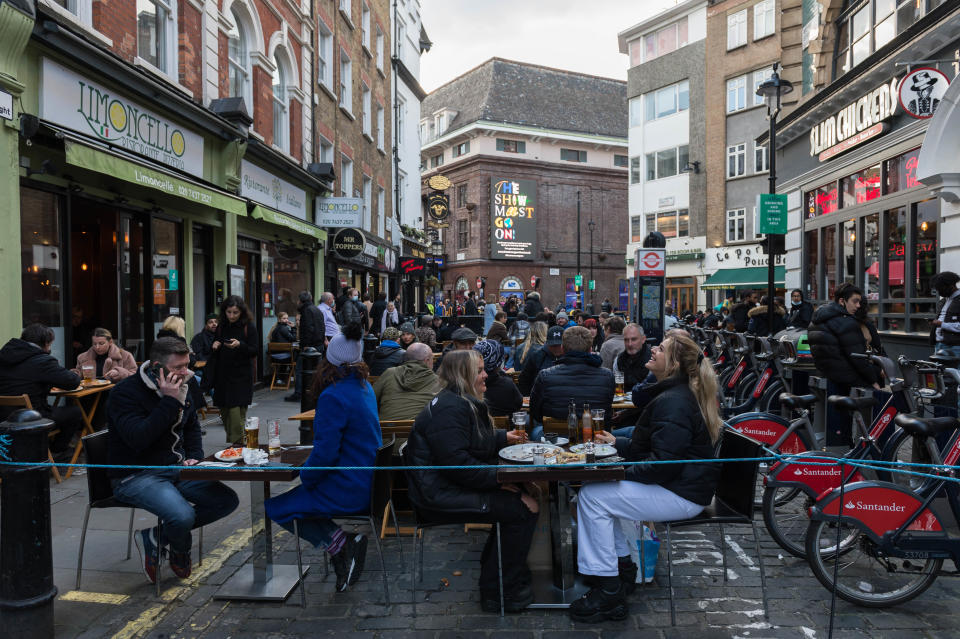 LONDON, UNITED KINGDOM - APRIL 12, 2021: Crowds fill tables in Old Compton Street in Soho, which is closed to traffic, as outdoor hospitality venues open their premises to customers after being closed for over three months under coronavirus lockdown, on 12 April, 2021 in London, England. From today the next stage of lifting lockdown restrictions goes ahead with pubs and restaurants allowed to serve food and drinks outdoors, opening of non-essential shops, hairdressers, beauty salons and gyms in England. (Photo credit should read Wiktor Szymanowicz/Barcroft Media via Getty Images)