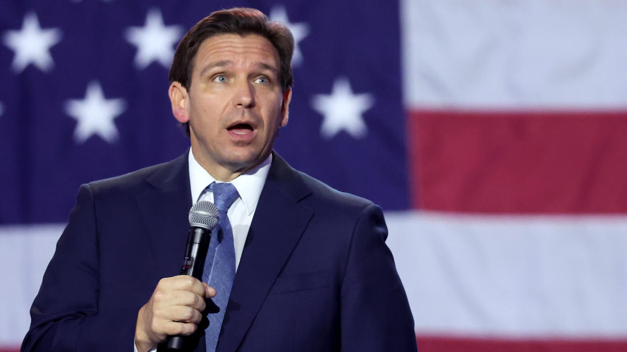Florida Governor Ron DeSantis holds a microphone as he speaks to Iowa voters.