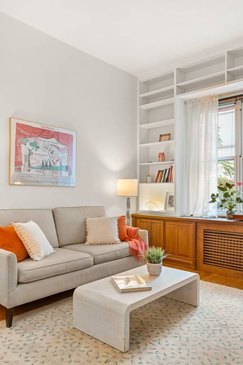 white living room with pale neutral sofa and tall built-in shelves around a window