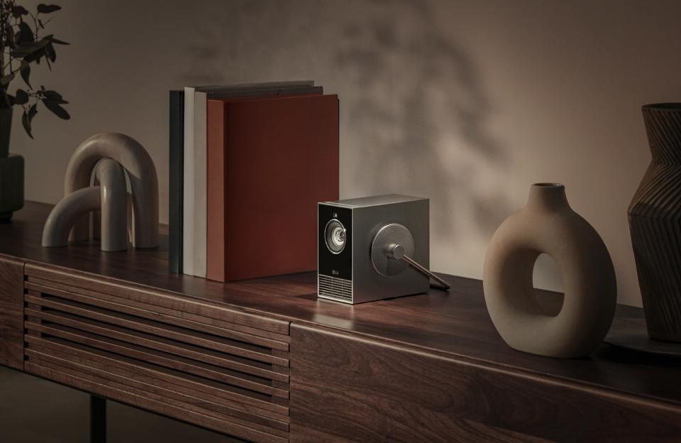 A projector on a mantle next to books and sculptures. 