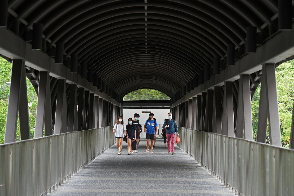 People walking on a pedestrian bridge along Bukit Timah Road in Singapore.