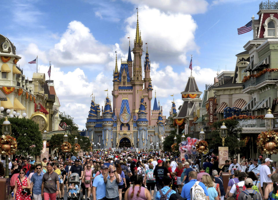 FILE - Crowds fill Main Street USA in front of Cinderella Castle at the Magic Kingdom on the 50th anniversary of Walt Disney World, in Lake Buena Vista, Fla., on Oct. 1, 2021. The Walt Disney Co. announced Thursday, May 18, 2023, that it was scrapping plans to build a new campus in central Florida and relocate 2,000 employees from Southern California. The decision follows a year of attacks from Gov. Ron DeSantis and the Legislature because the company opposed a state law that bans classroom lessons on sexual orientation and gender identity in early grades. (Joe Burbank/Orlando Sentinel via AP, File)