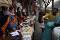 People wearing face masks buy food from a stall set up by a restaurant in Beijing