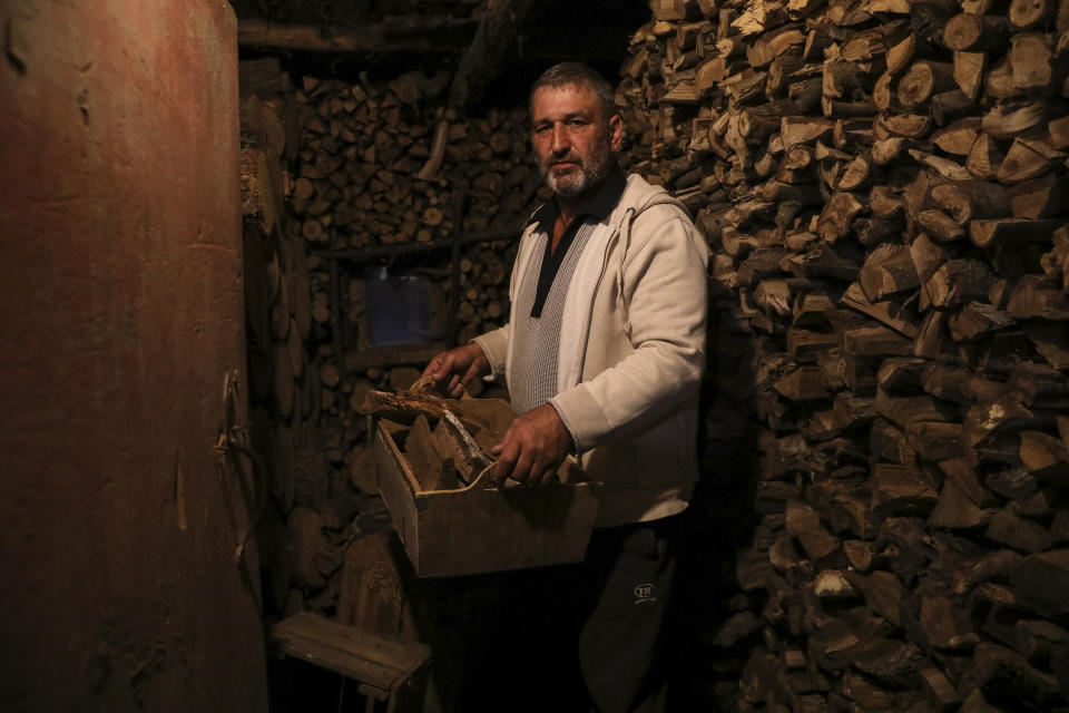 Gheorghe Batca carries firewood from a storage room to his house outside Chisinau, Moldova, Sunday, Oct. 16, 2022. Europe's energy crisis, triggered by Russia slashing natural gas flows amid its war against Ukraine, has forced some people to turn to cheaper heating sources like firewood as the weather gets colder. But as more people stock up and burn wood, prices have skyrocketed, shortages and thefts have been reported, and scams are emerging. (AP Photo/Aurel Obreja)