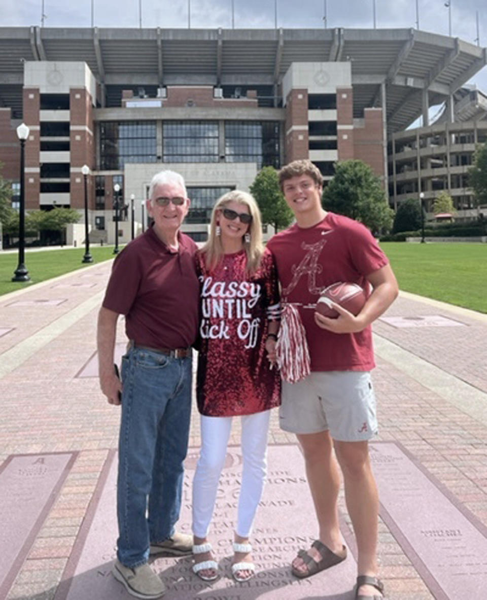 Former Alabama split end Dennis Homan, left, poses with his daughter Missy Homan, center, and grandson Kneeland Hibbett, a current Alabama long snapper, outside Bryant-Denny Stadium at the University of Alabama in Tuscaloosa, Ala. Hibbett has pledged to donate a share of his name, image and likeness proceeds to the Concussion Legacy Foundation, which has worked with ex-football players and others who developed traumatic brain injuries from repeated hits to the head. (Homan family photograph via AP)