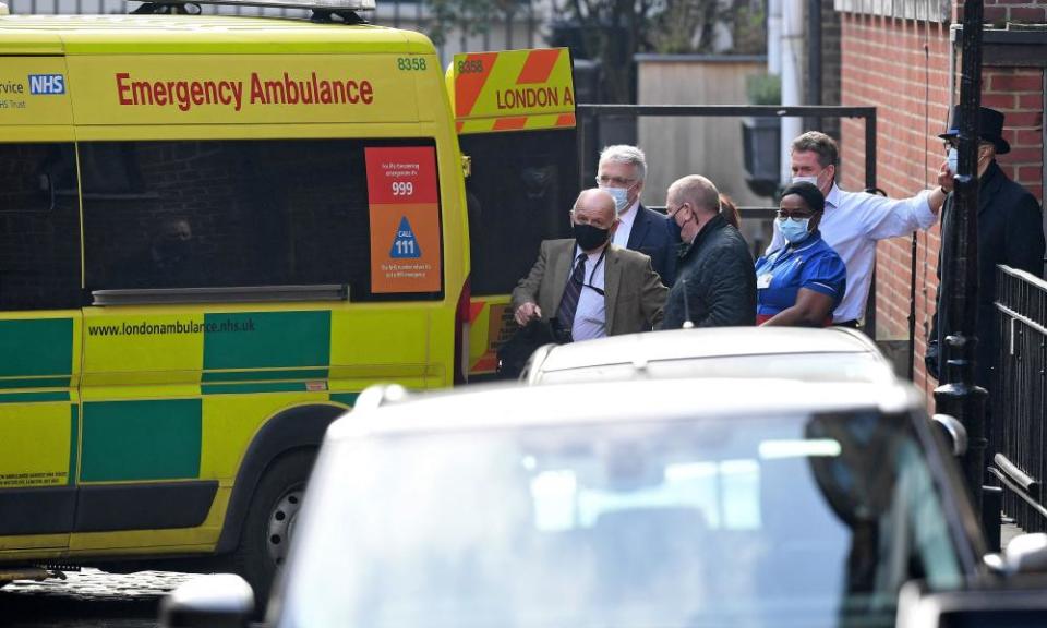 People gather around an ambulance parked outside the rear entrance of King Edward VII’s hospital