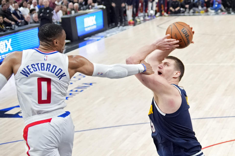 Denver Nuggets center Nikola Jokic, right, tries to shoot as Los Angeles Clippers guard Russell Westbrook fouls him during the second half of an NBA basketball game Thursday, April 4, 2024, in Los Angeles. (AP Photo/Mark J. Terrill)