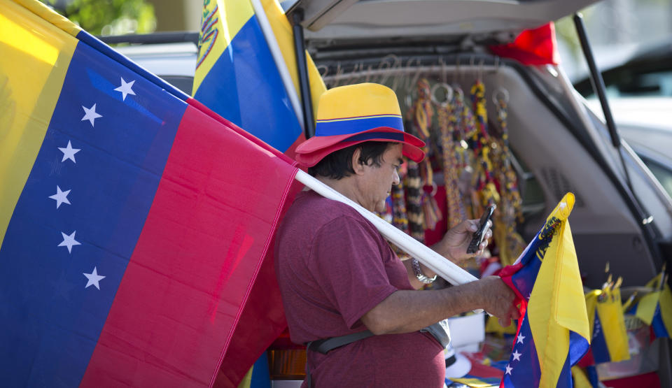 \Xidmara Landaeta carries his country's flag, offering them for sale, as Venezuelans from South Florida prepare for their bus trip to Washington, Thursday, May 8, 2014, in Doral, Fla. They are rallying to ask the Congress and President Barack Obama to impose economic sanctions and travel restrictions to the Venezuelan government officials because of presumed human right violations in the South American country. Organizers said they expect Venezuelans from 19 states will meet in Washington on Friday to demonstrate in front of the White House, Congress and the Organization of American States. (AP Photo/J Pat Carter)