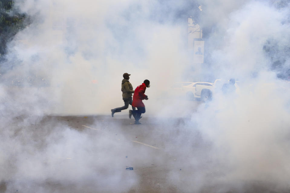 Protestors run through clouds of tears during anti-government protests in Kenya's capital Nairobi, Thursday, Aug. 8, 2024. (AP Photo/Patrick Ngugi)