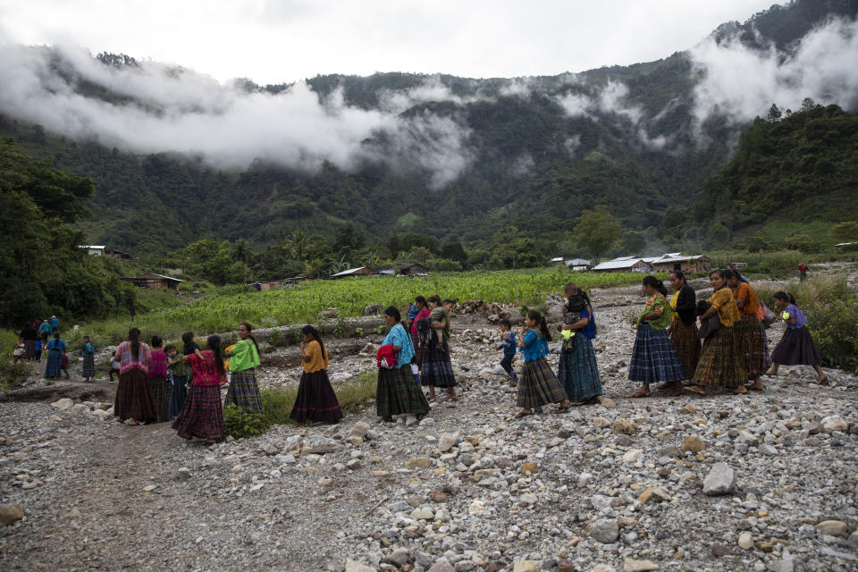 After attending a church service, women and children walk to a communal meeting to try and solve problems associated with housing and donations received by the international community, in the makeshift settlement Nuevo Queja, Guatemala, Sunday, July 11, 2021. The government of Guatemala has declared the settlement uninhabitable, making the community ineligible for electric poles, road repairs or improved water supply. (AP Photo/Rodrigo Abd)