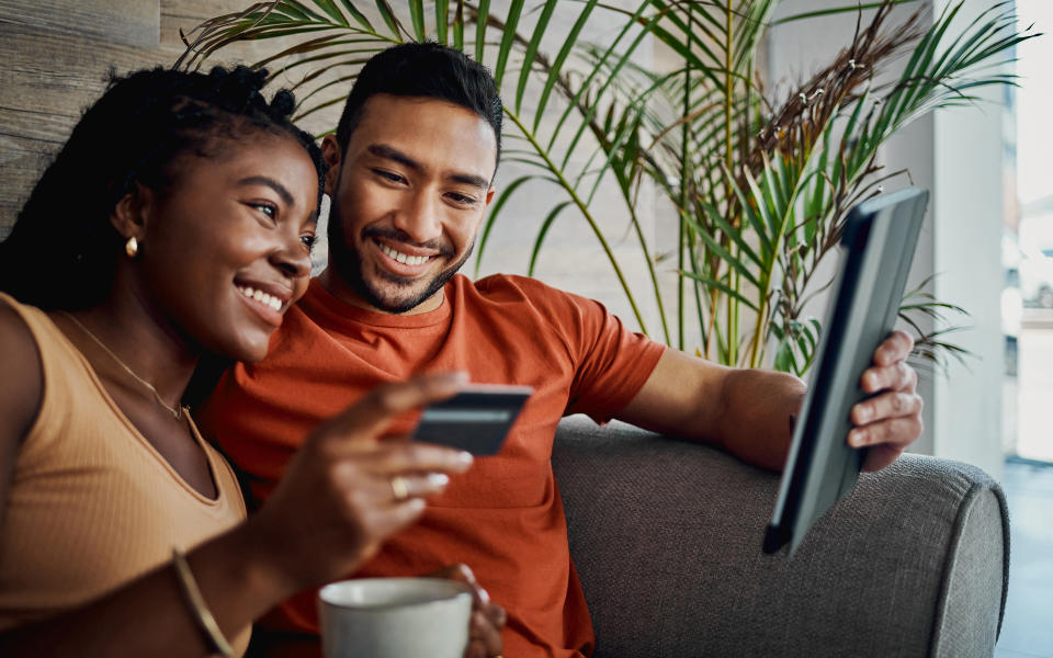 Black couple using tablet together and inputting credit card information online.