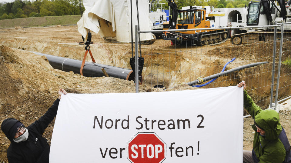 Activists occupy a German pipeline building site in Wrangelsburg, northern Germany, Thursday, May 16, 2019. Police say activists have occupied a building site in northern Germany to protest against the ongoing Nord Stream 2 pipeline project with Russia. The sign reads 'Nord Stream 2 plug of'. (Stefan Sauer/dpa via AP)