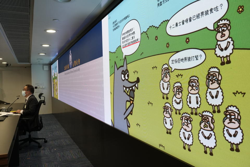 Li Kwai-wah, left, senior superintendent of Police National Security Department speaks in front of a screen showing evidence including the contents of three children's books on stories that revolve around a village of sheep which has to deal with wolves from a different village, before a press conference in Hong Kong Thursday, July 22, 2021. Hong Kong's national security police on Thursday arrested five people from a trade union of the General Association of Hong Kong Speech Therapists on suspicion of conspiring to publish and distribute seditious material, in the latest arrests made amid a crackdown on dissent in the city. (AP Photo/Vincent Yu)