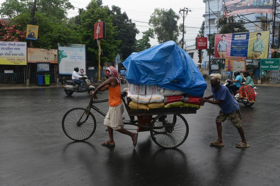 Men push a tricycle cart with a plastic sheet covering the load during a rainfall in Siliguri on May 20, 2020. (Photo by DIPTENDU DUTTA / AFP) (Photo by DIPTENDU DUTTA/AFP via Getty Images)