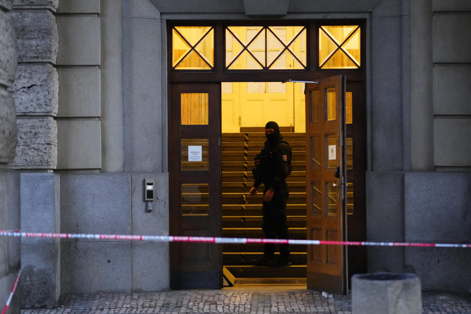 A policeman stands in doors of the building of Philosophical Faculty of Charles University Prague, Czech Republic, Friday, Dec. 22, 2023. A lone gunman opened fire at a university on Thursday, killing more than a dozen people and injuring scores of people. (AP Photo/Petr David Josek)
