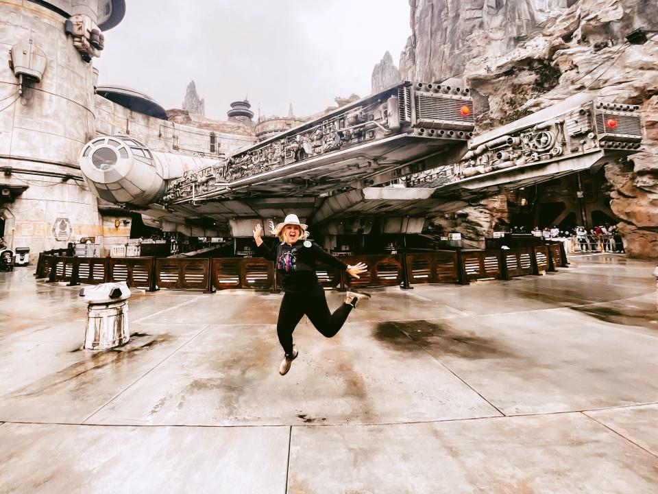 ali jumping for a posed photo in front of the millenium falcon in galaxy's edge at disneyland