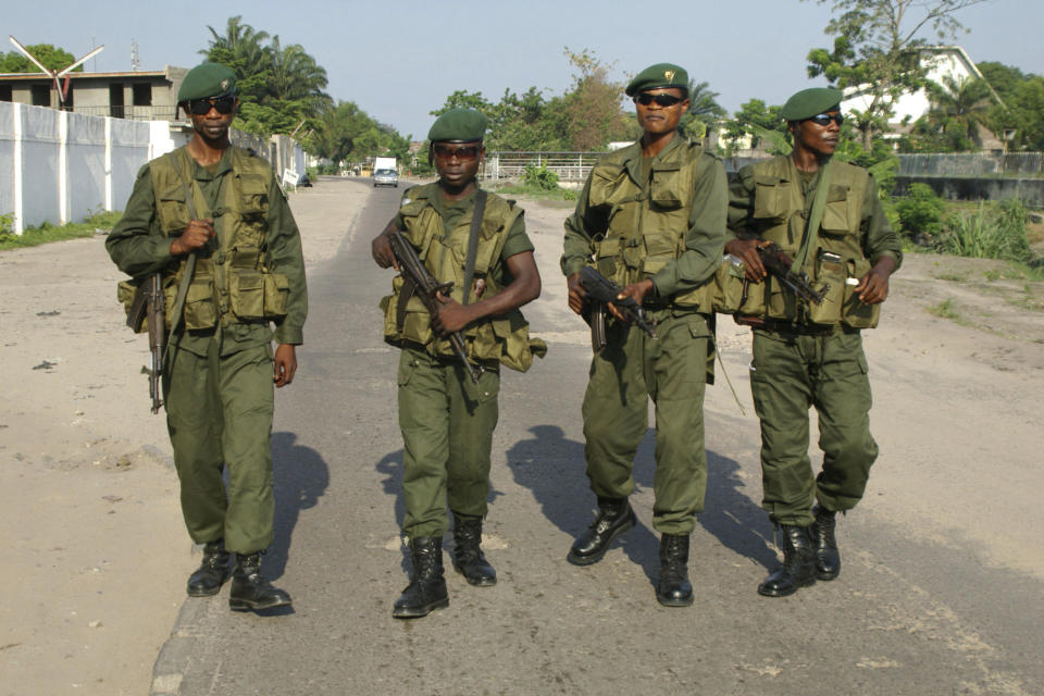 FILE - In this Oct.22 2006 file photo shot by AP contributing photographer John Bompengo, Congolese army soldiers carry guns as they walk down a street in Kinshasa, Democratic Republic of Congo. Relatives say longtime Associated Press contributor John Bompengo has died of COVID-19 in Congo's capital. Bompengo, who had covered his country's political turmoil over the course of 16 years, died Saturday, June 20, 2020 at a Kinshasa hospital. (AP Photo/John Bompengo, file)