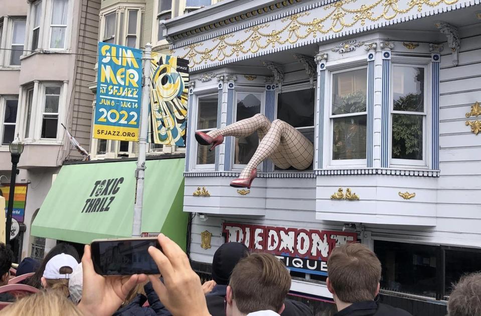 A pair of shapely, lady legs flail from the second floor of a Victorian building over the Piedmont Boutique in the Haight-Ashbury neighborhood of San Francisco in July 2022.