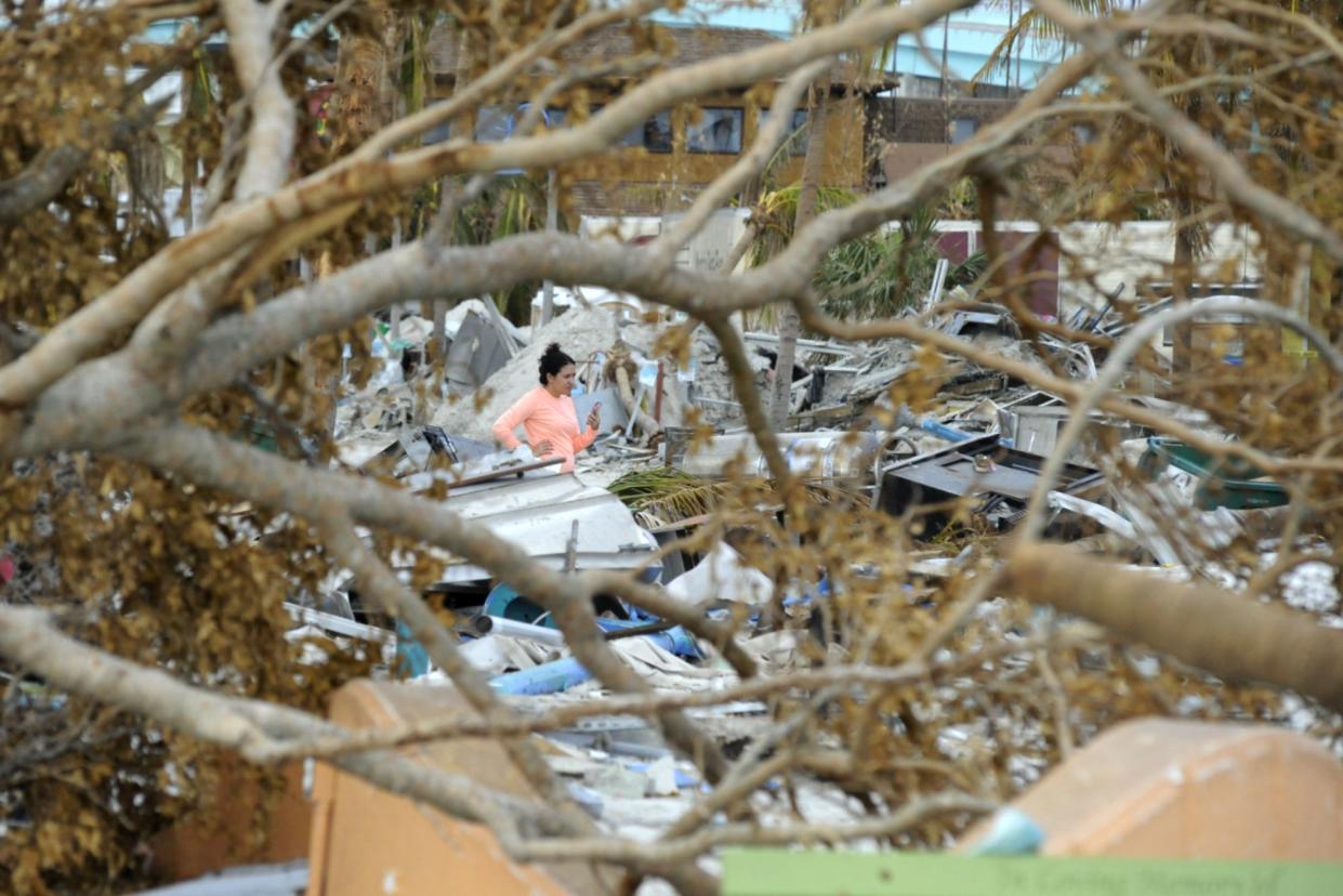 Alexa Alvarez talks to her fiancé while standing amid the rubble of Fort Myers Beach, Fla., on Sunday, Oct. 9, 2022. Hurricane Ian pummeled the coastal barrier island, and residents spent the weekend assessing damage and beginning to clean up. Alvarez's parents lost their home to the storm.