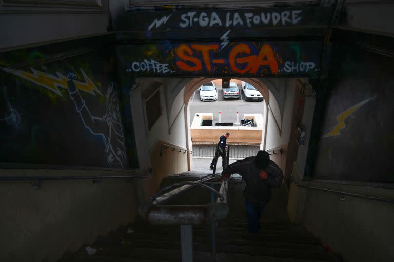 Un policía (izq.) patrulla cerca de una escalera en busca de presuntos traficantes en el distrito norte de Marsella, sur de Francia. Varios juicios recientes con cargos que incluyen violación y tortura han subrayado el abuso que son víctimas de algunos traficantes de drogas de poca monta. por distribuidores más establecidos en Marsella. (Photo by Christophe SIMON / AFP)