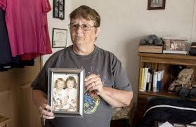 Dixie Clark shows a photo of her and her older sister Barbara Conley.  They sisters and their brother, David Bauer, were abandoned by their mother and later adopted separately.