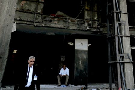 Security guards are seen in front of the damaged facade of the National Cancer Institute after an overnight fire from a blast, in Cairo