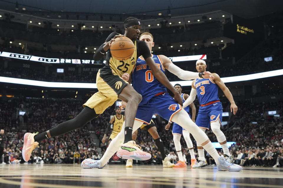 Toronto Raptors forward Chris Boucher (25) drives to the basket while New York Knicks guard Donte DiVincenzo (0) defends during first-half NBA basketball game action in Toronto, Friday, Dec. 1, 2023. (Arlyn McAdorey/The Canadian Press via AP)