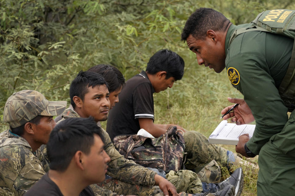 A group of migrants are processed after being apprehended by U.S. Border Patrol agents in the desert at the base of the Baboquivari Mountains, Thursday, Sept. 8, 2022, near Sasabe, Ariz. The desert region located in the Tucson sector just north of Mexico is one the deadliest stretches along the international border with rugged desert mountains, uneven topography, washes and triple-digit temperatures in the summer months. Border Patrol agents performed 3,000 rescues in the sector in the past 12 months. (AP Photo/Matt York)