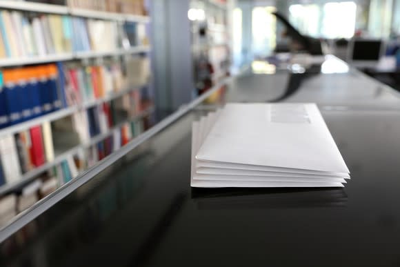 A stack of envelopes sits on a counter in an office.