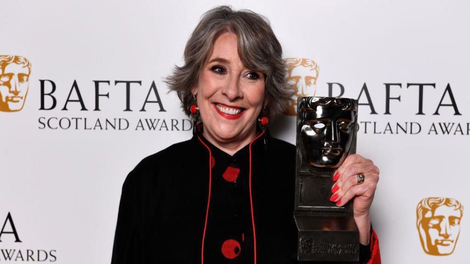 Phyllis Logan holding a BAFTA
