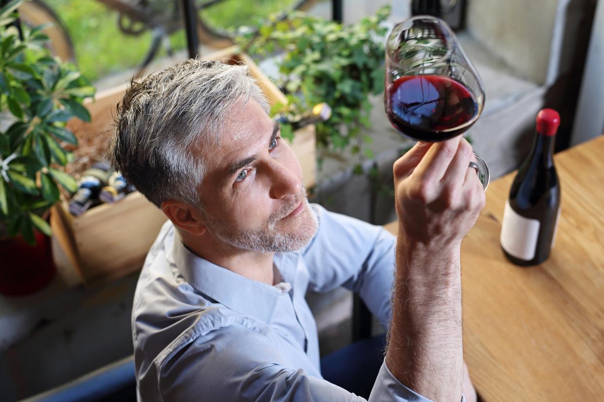 man tasting red wine and looking at it