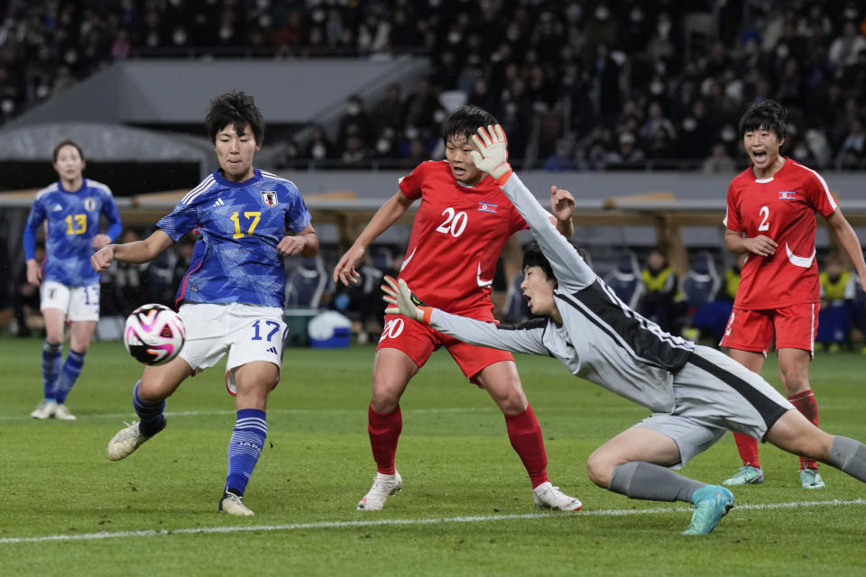 Japan's Kiko Seike, left, prepares to kick the ball in an attempt to score as North Korea's goalkeeper Pak Ju Mi dives in to save the ball during the final qualifier for the Paris Olympic women's football tournament at the National Stadium Wednesday, Feb. 28, 2024, in Tokyo. (AP Photo/Eugene Hoshiko)