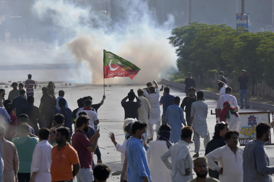 FILE - Supporters of Pakistan's former Prime Minister Imran Khan block a road as police fire tear gas shell to disperse them during a protest against the arrest of their leader, in Karachi, Pakistan, Tuesday, May 9, 2023. The arrest of Khan earlier this week has shown how quickly his fervent loyalists can mobilize in large numbers. (AP Photo/Fareed Khan, File)