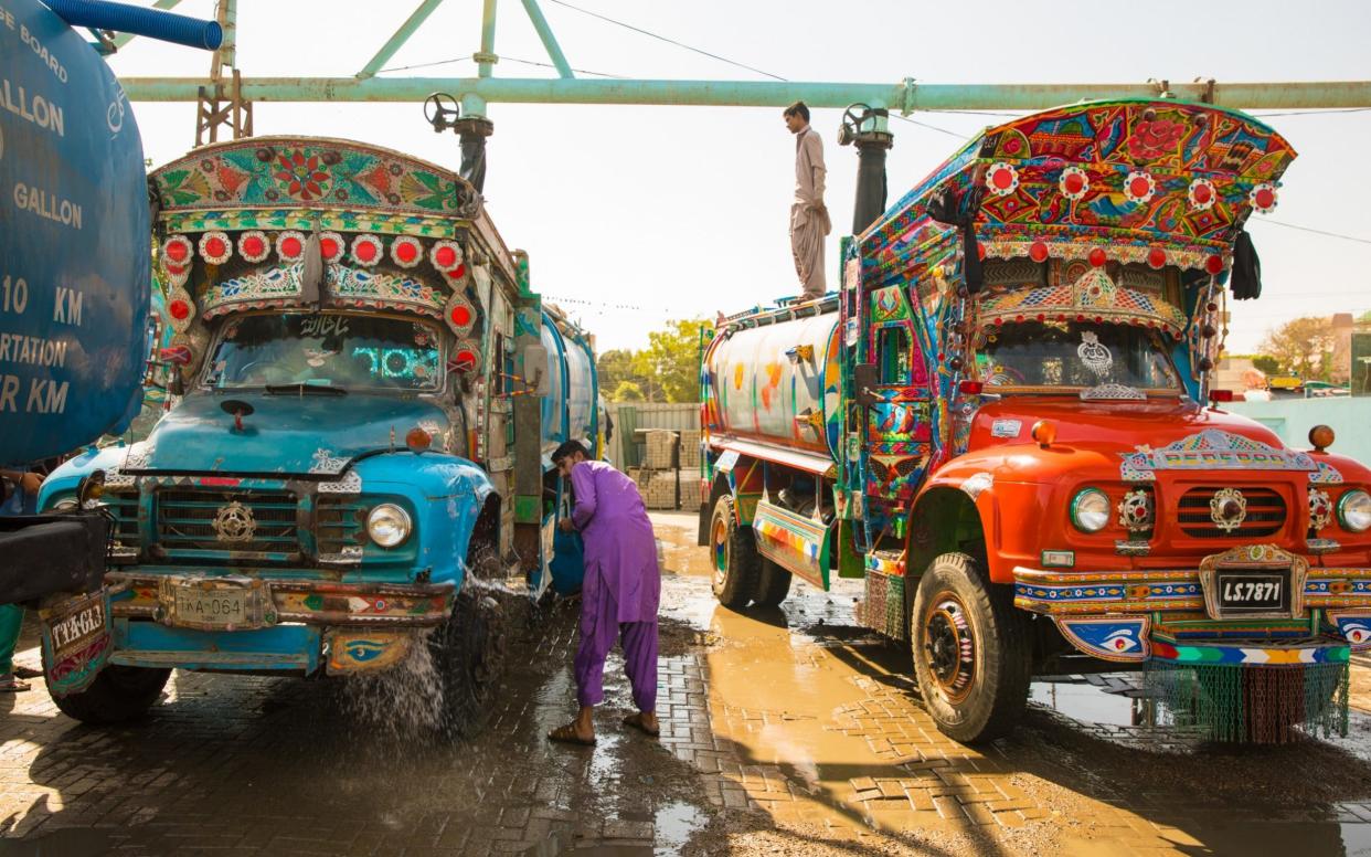 A man washes the tyre of a water tanker as it fills up at the legal hydrant in Sakhi Hassan in Karachi - Insiya Syed/The Telegraph