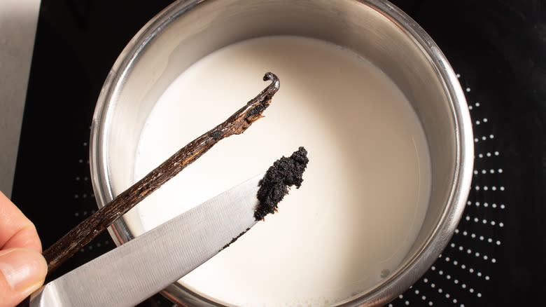 Adding vanilla bean and seeds to a saucepan with milk