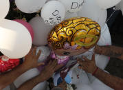 Family members place balloons and flower arrangements on the grave of 7-year-old murder victim Fatima in Mexico City, Tuesday, Feb. 18, 2020. Fatima's body was found wrapped in a bag and abandoned in a rural area on Saturday. Five people have been questioned in the case, and video footage of her abduction exists. (AP Photo/Marco Ugarte)