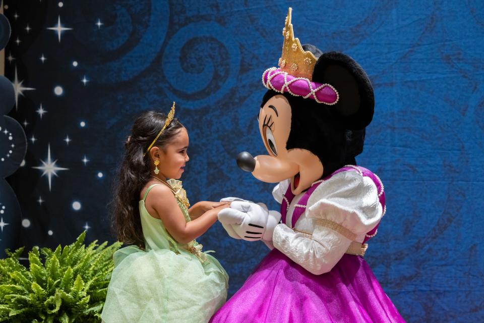 Mia Rodriguez and Minnie Mouse hold hands at the Once Upon a Wish Party.