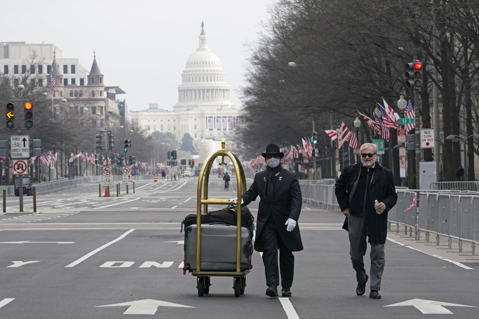 Danish Rozario, left, of Silver Spring, Md., wheels the baggage down Pennsylvania Avenue for a guest at the Trump Hotel in Washington, Friday, Jan. 15, 2021, ahead of the inauguration of President-elect Joe Biden and Vice President-elect Kamala Harris.Between the still-raging pandemic and suddenly very real threat of violence from supporters of outgoing President Donald Trump, Jan. 20 promises to be one of the most unusual presidential inaugurations in American history. Joe Biden and Kamala Harris will take the oath of office outside the Capitol. (AP Photo/Susan Walsh)