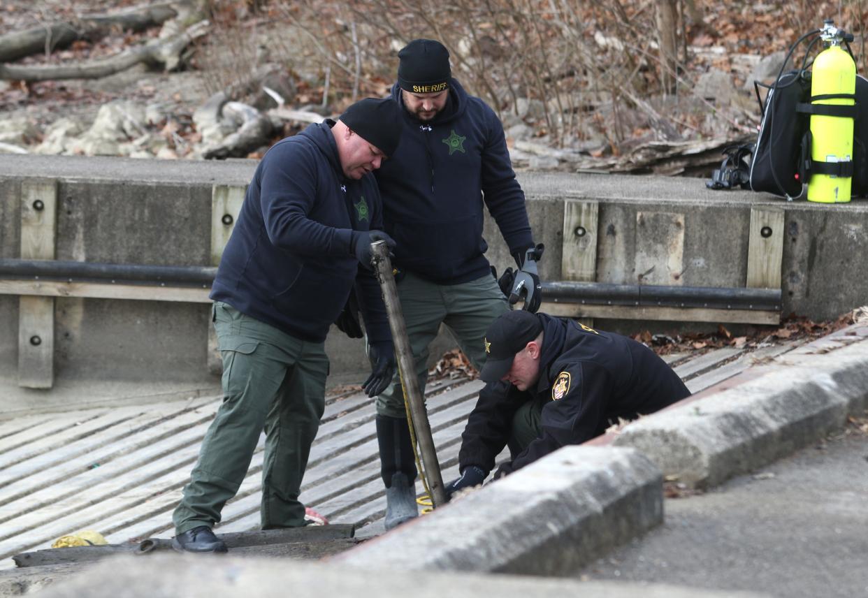 Members of the Franklin County Sheriff's Office dive team clean off a magnet being used to search Dillon Lake near Zanesville on Tuesday. Muskingum County Sheriff Matt Lutz said the team and Licking County Sheriff's Office detectives were hoping to find a weapon used in a shooting near Toboso last week.