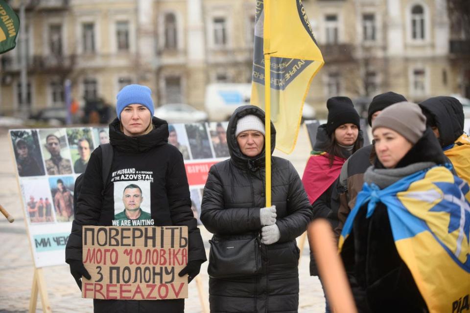 Protesters hold signs and flags in Kyiv