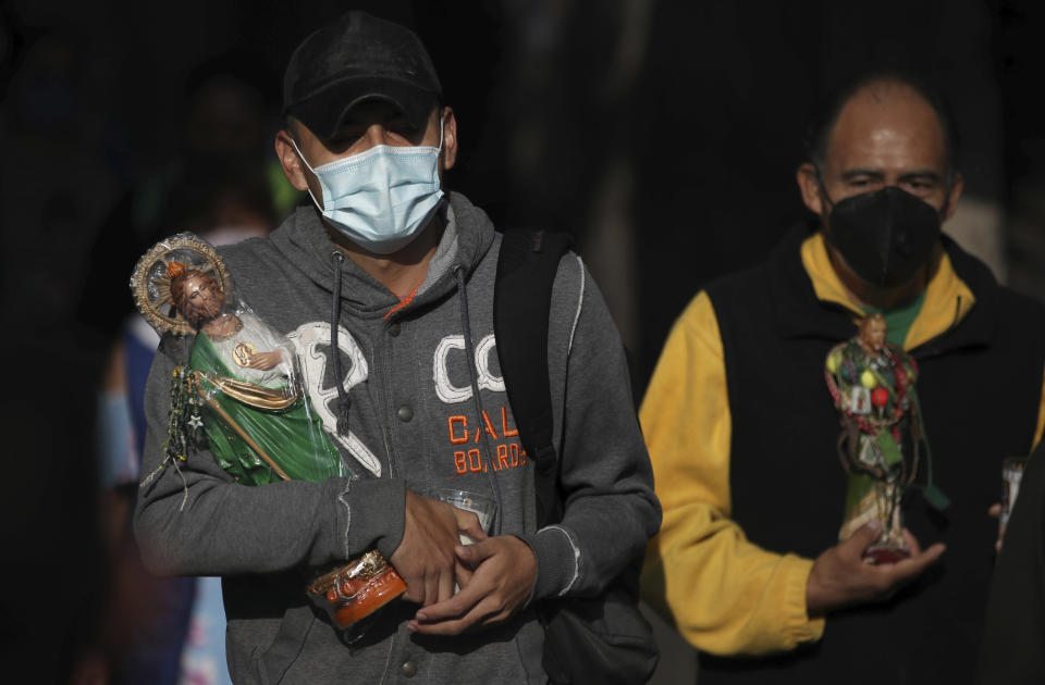 Devotos cargando estatuas y con una mascarilla protectora para protegerse del nuevo coronavirus llegan a la iglesia católica San Hipólito como parte de la peregrinación anual en honor a San Judas, el santo patrón de las causas perdidas, en la Ciudad de México, el miércoles 28 de octubre de 2020. (AP Foto/Marco Ugarte)