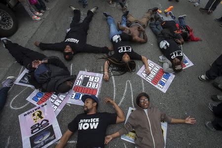 Residents carrying signs stage a 'die-in' rally on a street of west Baltimore, Maryland May 1, 2015. REUTERS/Adrees Latif